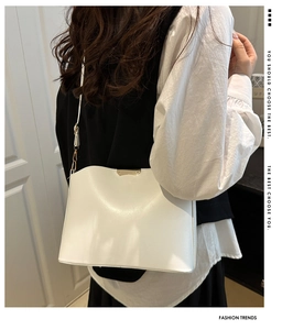 Vue détaillée du sac coquille blanc avec texture cuir lisse et boucle en métal doré