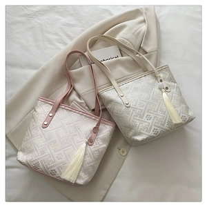 Detail of jacquard tote bags with tassel charms and intricate floral woven textures