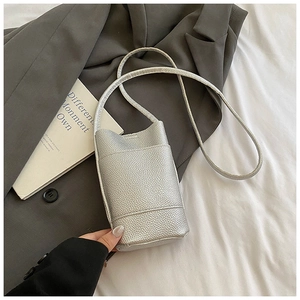 Detail of silver pebble grain leather mobile crossbody bag on elegant fabric background