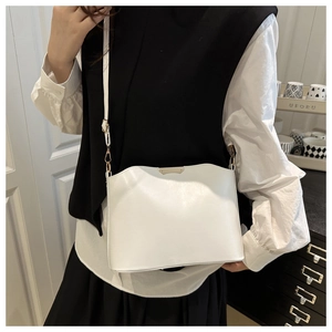 Detail of white leather crossbody bag with metallic trim and adjustable shoulder strap