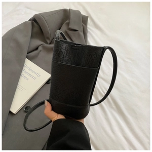 Detail view of black lychee texture bucket bag with functional front pocket and strap
