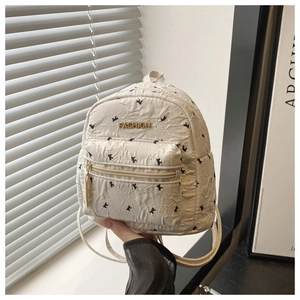 Detail of mini cream quilted backpack featuring black puppy prints and gold metal logo