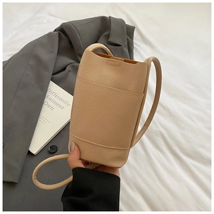 Detail of minimalist beige lychee leather mini crossbody bag with sleek textured surface