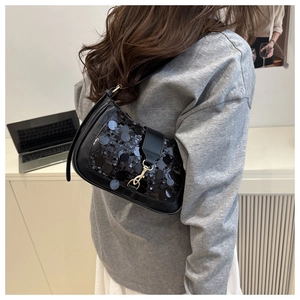 Close-up of stylish black sequin shoulder bag with metallic clasp detail on a model