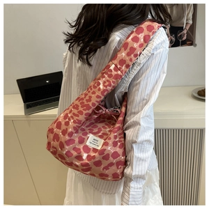 Detailed view of pink leopard print tote bag featuring a bow accent and wide shoulder strap