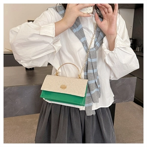Detail of woven straw and green leather patchwork bag with gold metal circular handle
