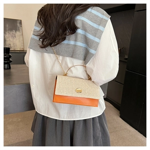 Detail of woven beige texture and orange leather flap with gold metal chain strap