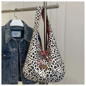 Detail of leopard print canvas tote with Fashion tag and red bow on white background
