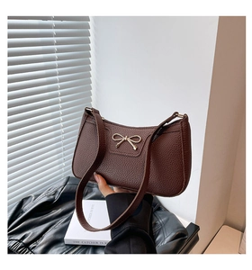 Detail of vintage brown pebble grain bag with a decorative gold bow metal buckle