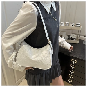 Close-up detail of white faux crocodile texture on a minimalist chic shoulder bag