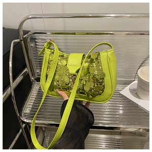 Detail of neon green baguette bag with large sequins and adjustable leather strap