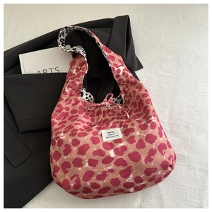 Detail of leopard print tote bag featuring a decorative pink bow and stylish fabric label