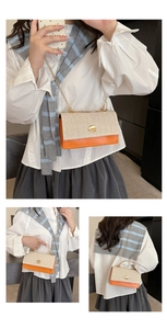 Detail of woven straw shoulder bag with orange leather trim and gold chain handle