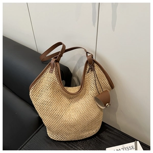 Detail of woven straw tote bag with brown leather trim and adjustable shoulder strap