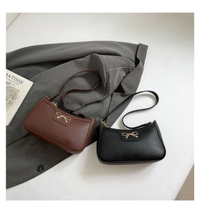 Detail of lychee textured leather bag with metallic gold bow and crescent shape