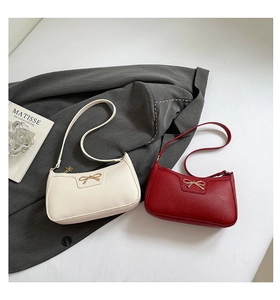 Detail view of cream and red leather underarm bags with gold bow and flower charm