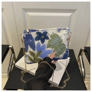 Détail de la broderie florale bleue sur la pochette de soirée à paillettes et chaîne
