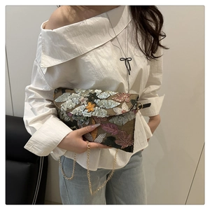 Detail van geborduurde enveloppe-clutch met pailletten en fijne gouden ketting voor dames