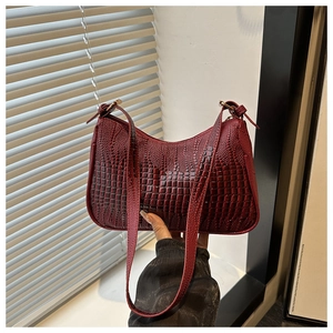 Detail of burgundy crocodile-embossed leather underarm bag with vintage gold buckle