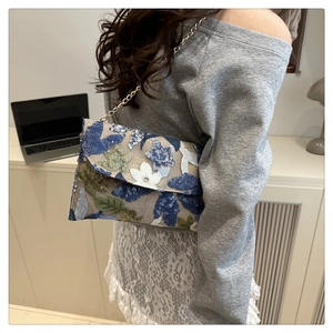 Detail van florale pailletten borduurwerk en gouden ketting aan de elegante avondclutch