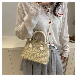 Detalle de bolso de paja tejida con asas de cuero blanco y cremalleras dobles de metal