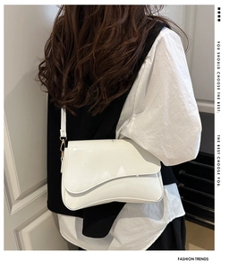 Detail of white patent leather crossbody bag with wave design shown on a model