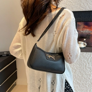 Large black lychee pattern leather baguette bag with golden bow knot held by model