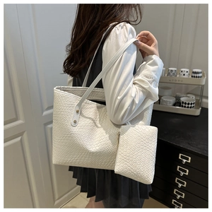 Close-up detail of white woven texture on a large tote bag with matching pouch set