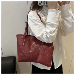 Detail of burgundy woven tote bag set with golden studs showing material texture