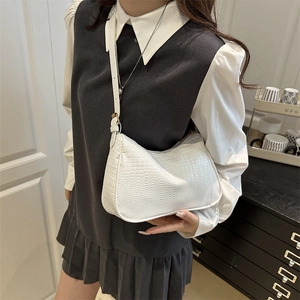 Minimalist white crocodile embossed leather crescent shoulder bag worn by a model