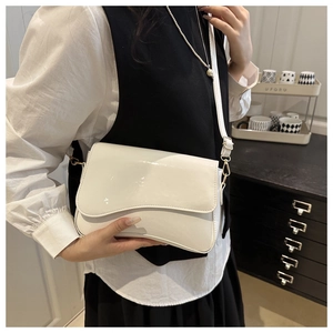 Detailed view of glossy white patent leather crossbody bag with elegant wavy flap and gold buckle