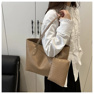 Detail of light brown woven tote bag featuring matching small inner pouch and slim straps
