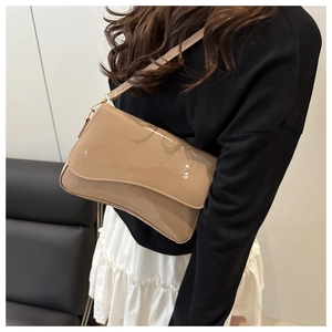 Close-up of beige patent leather shoulder bag with a unique wave-shaped flap design