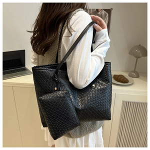 Detail of black woven tote bag and small matching zipper pouch in a cozy office setting