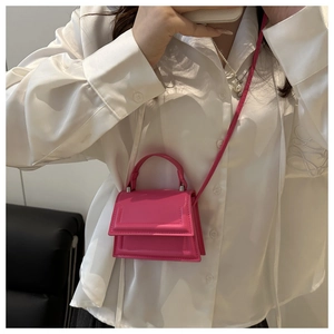 Detailed close-up of fuchsia micro handbag with curved handle and sleek finish