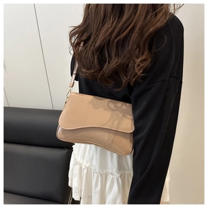 Detail of khaki patent leather shoulder bag with unique wavy edge and glossy finish