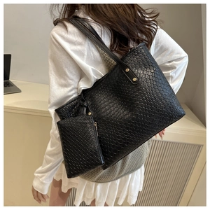 On-shoulder view of black woven leather tote bag with a matching mini zipper pouch