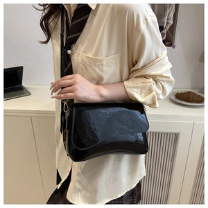 Glossy patent leather shoulder bag detail with adjustable strap on professional model