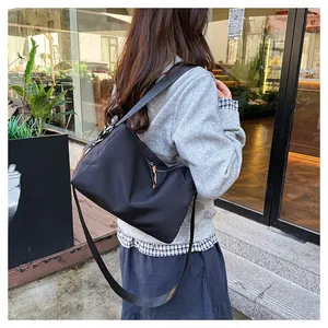 Détail d'un sac bandoulière en nylon noir avec tirette de fermeture éclair orange vif