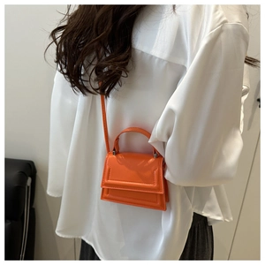Detailed view of mini orange leather crossbody bag with quilted edges and top handle