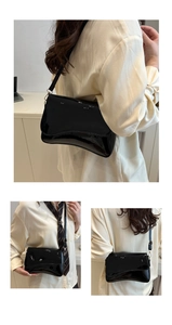 Close-up of glossy patent leather texture and gold hardware on black shoulder bag