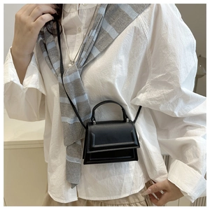 Detailed view of black minimalist mini crossbody bag featuring a matte leather finish