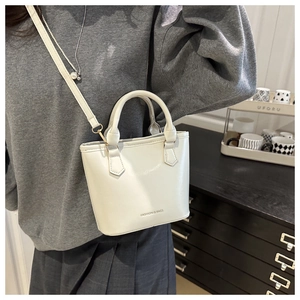 Close-up of white leather bucket bag with Fashion & Bags text and fine metal strap