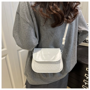 Detailed back view of a white quilted crossbody bag with gold fashion trend lettering