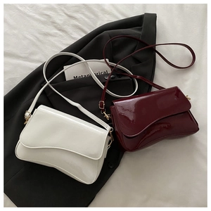 Detail of white and burgundy glossy patent leather shoulder bags with gold hardware