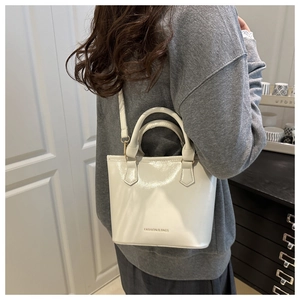 Model wearing a white patent leather bucket bag with Fashion & Bags logo print