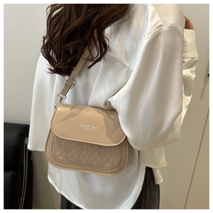 Close-up of beige crossbody bag featuring diamond quilted texture and fashion lettering