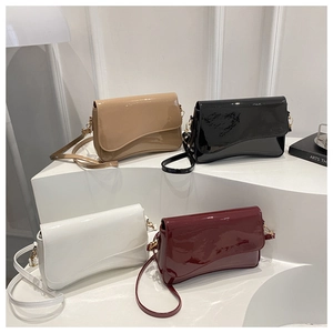 Detail view of four glossy patent leather crossbody bags in cream, black, white, and wine red