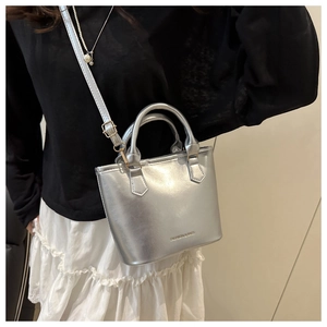 Détail d'un sac seau argenté métallisé avec doubles poignées et lettrage fashion