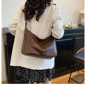 Détail de la large bandoulière réglable sur un sac cabas en cuir marron foncé